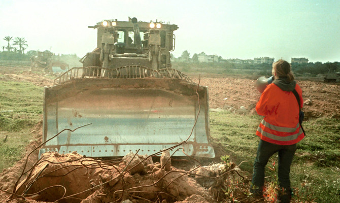 American peace activist Rachel Corrie tries to stop an Israeli bulldozer from destroying Palestinian homes on March 16, 2003, in a refugee camp in the Gaza Strip. 