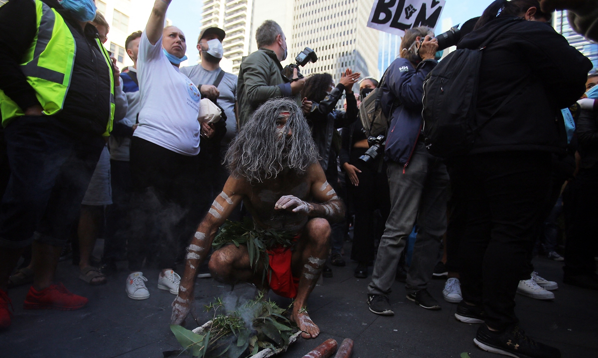 An Indigenous Australian participates in a smoking ceremony in front of Sydney Town Hall during a protest against Aboriginal deaths in custody in Sydney, Australia on June 6, 2020. Many thousands have rallied in Sydney CBD to stop Aboriginal deaths in custody after an appeal court's last-minute decision to authorise the public gathering. Photo: AFP